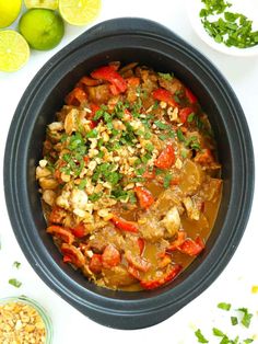 a bowl filled with food next to limes and other ingredients on a white surface