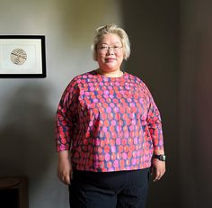 an older woman standing in front of a wall