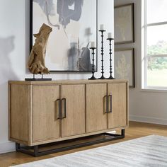 a wooden sideboard with metal handles in a living room next to a large window