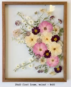 a wooden frame with flowers in it hanging on the wall next to a white wall