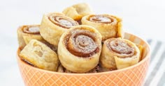 a bowl filled with cinnamon rolls on top of a table