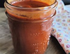 a jar filled with sauce sitting on top of a wooden table