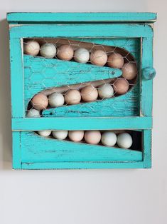 an old wooden box with eggs in it on a white wall next to a blue frame