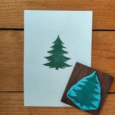 a rubber stamp with a pine tree on it next to a piece of paper that has been cut into the shape of a christmas tree