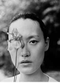 a woman holding a flower in front of her face