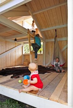 two children playing with toys on the floor in a room that is made out of wood