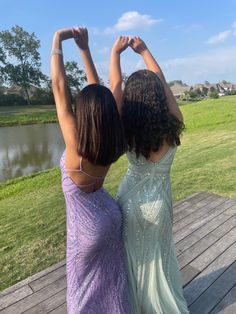 two women in dresses standing on a wooden deck