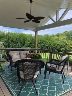 two wicker chairs sitting on top of a blue rug under a white ceiling fan