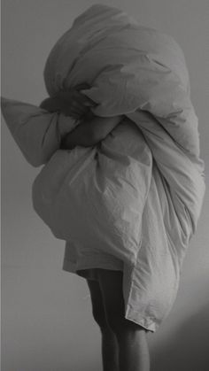 a black and white photo of a person wrapped in a blanket with their head down