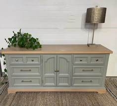 a grey dresser with drawers and a plant on top