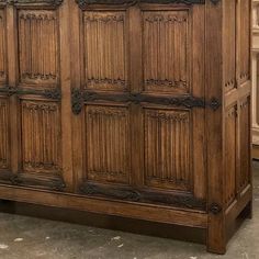 a large wooden cabinet sitting on top of a floor next to a wall mounted clock