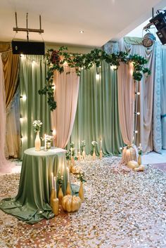 a table with flowers and candles on it in front of a curtained stage backdrop