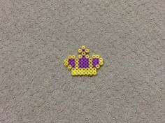 a yellow and purple beaded brooch sitting on top of a gray carpeted floor