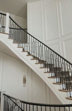 a white staircase with wrought iron railing and handrails next to a large door