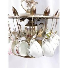 a silver tray with cups and spoons hanging from it's side, filled with teacups and saucers