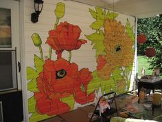 an outdoor covered porch with flowers painted on the wall