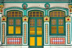 an ornately painted building with yellow shutters on the front and green doors,