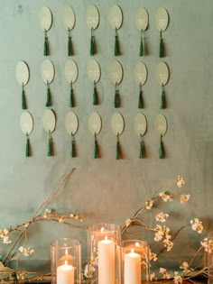 several candles are lit in front of a wall with many plates on it and flowers