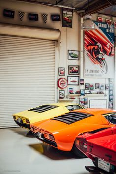 three orange and one red sports cars are parked in a garage next to each other