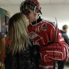 a man and woman kissing while wearing hockey gear