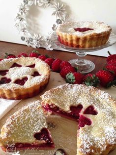 two pies on a table with strawberries and one is cut in half to show the filling