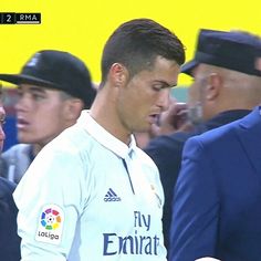 a man in white shirt standing next to other men wearing blue suits and hats at a soccer game