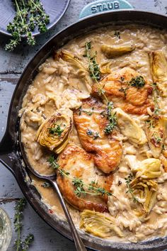 a skillet filled with chicken and artichokes covered in gravy