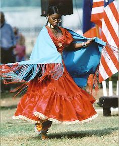 a woman in a red and blue dress dancing with an american flag on the other side