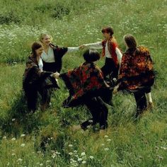 four women are sitting in the grass and one is holding another woman's hand