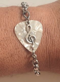 a close up of a person's wrist with a musical note charm on it