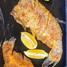 some fish and lemons on a black plate