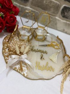 a plate with some gold and white decorations on it next to red rose bouquets