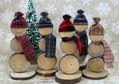 several wooden logs with hats and scarves on them, sitting next to a small christmas tree