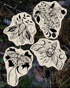 four stickers with moths on them in the grass and some plants behind them,