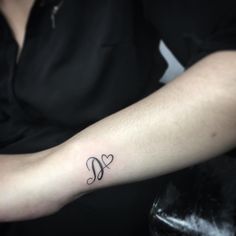 a woman's arm with a small heart tattoo on the left side of her arm