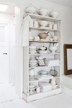 a white shelf filled with lots of dishes on top of it's sides in a room