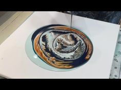 a bowl is sitting on top of a white table with blue and brown swirls