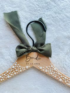 a wooden hanger with the name bride written on it and a green ribbon tied to it