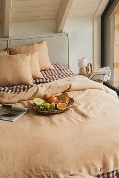 a bed with a basket of fruit on top of it next to an open window