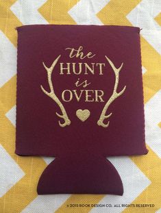 the hunt is over koozie with deer antlers and hearts in gold on maroon