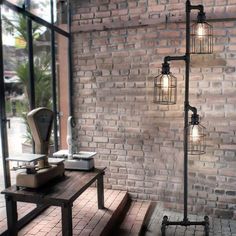 a brick wall with three light fixtures on it and a wooden table in front of it