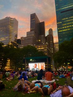 many people are sitting in the grass watching movies