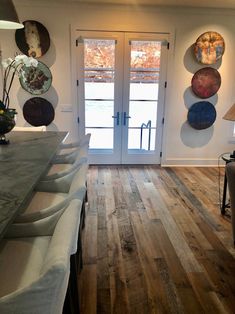 a kitchen with wooden floors and white walls, two large doors leading to the outside