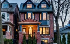 a large brick house with lots of windows and lights on the front door is lit up at night