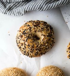 three sesame seed bagels sitting on top of white parchment paper next to each other