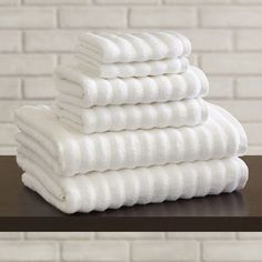 a stack of white towels sitting on top of a wooden table next to a brick wall