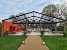 a walkway leading to an orange building with tables and chairs in the front lawn area