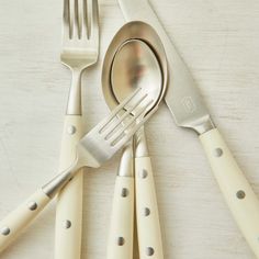 a set of five forks and spoons on a white table with polka dot design