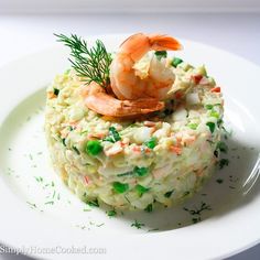 a white plate topped with rice covered in shrimp and garnished with parsley