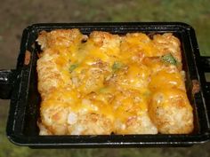 a person holding up a casserole dish with cheese and meat on it in their hand